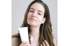 A woman applies face cream.